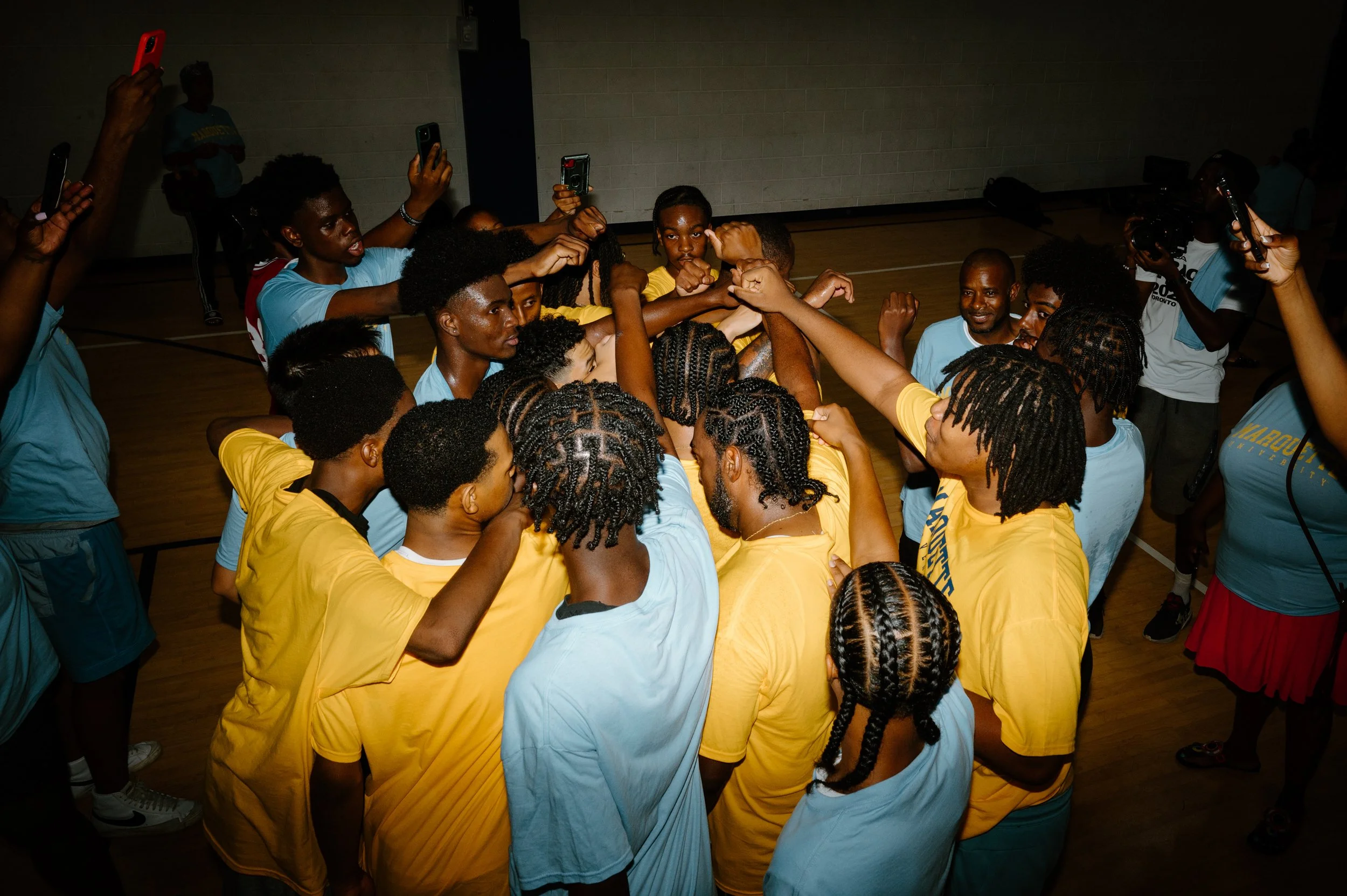 Documentary photo of the Marquette basketball team gathered together in a huddle during practice