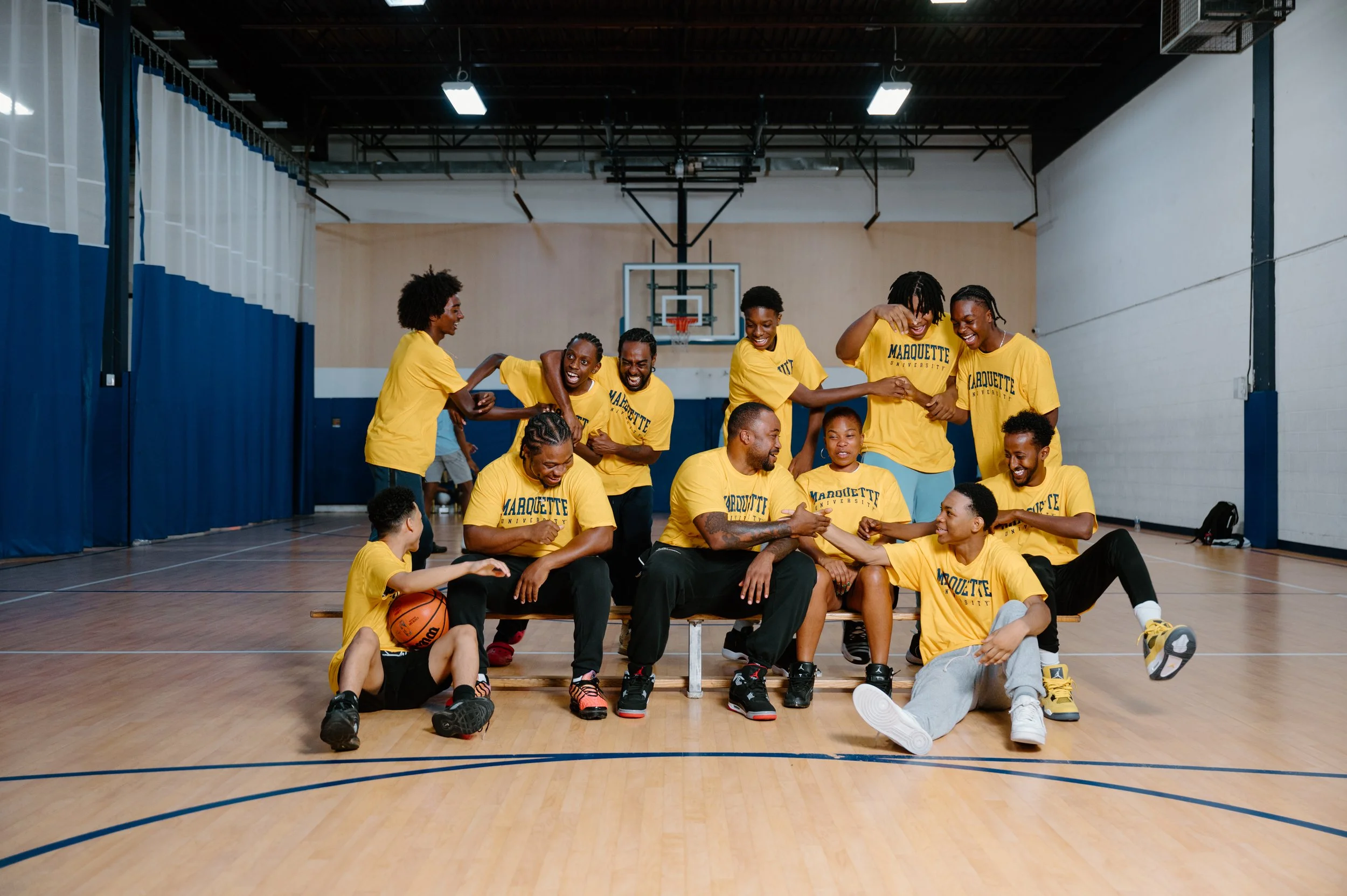 Candid group photo of Junior Cadougan and his Marquette basketball teammates sitting together and interacting during a team session