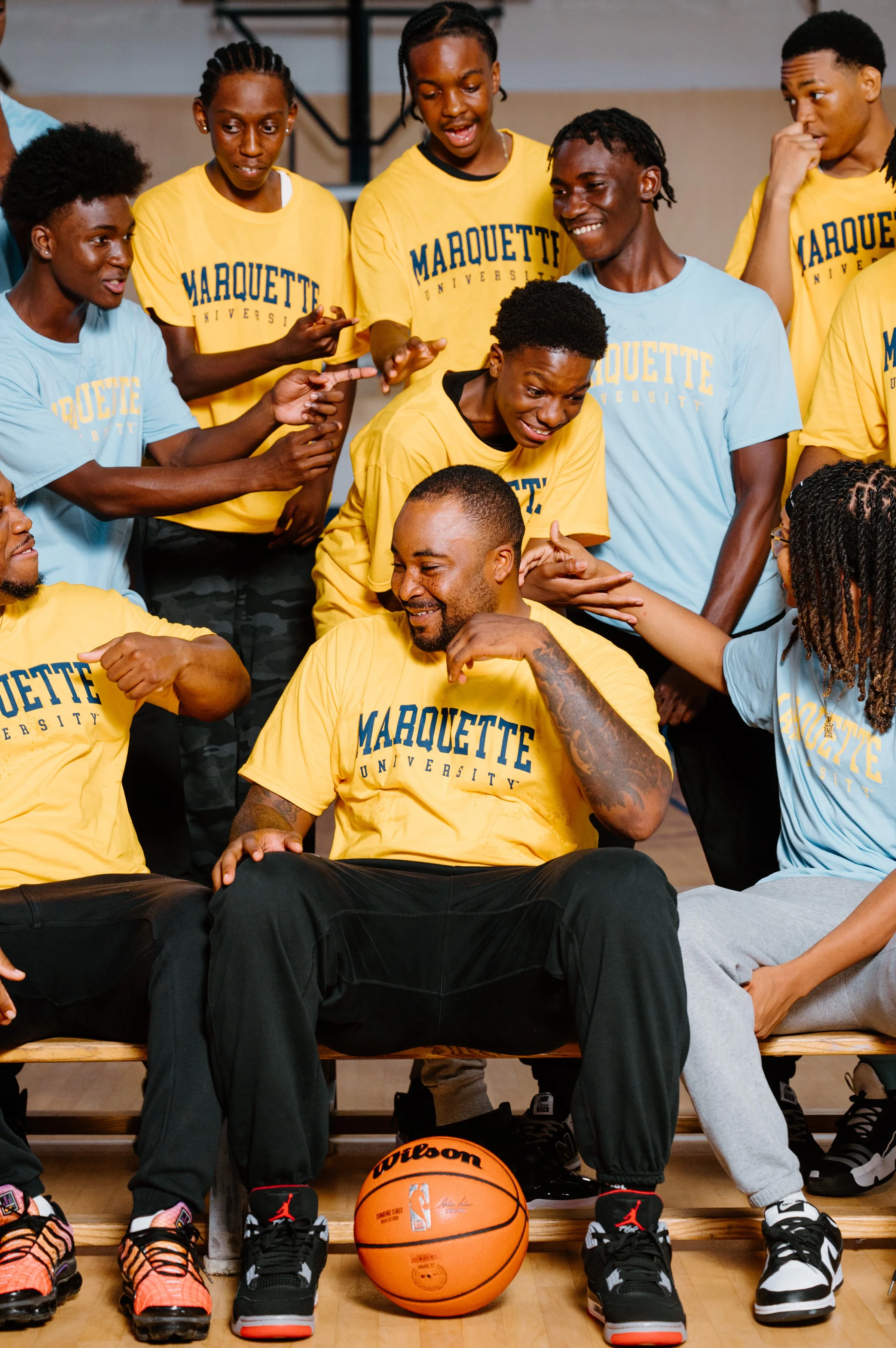 Close editorial portrait of Junior Cadougan surrounded by smiling and laughing Marquette teammates