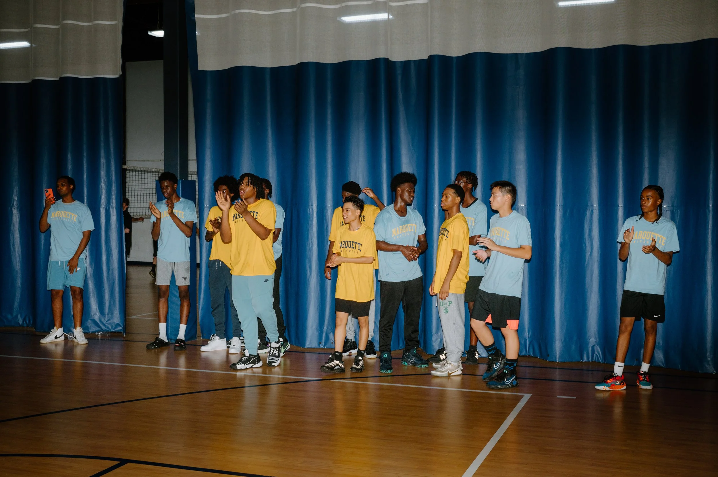 Documentary photo of Marquette basketball players standing at the sideline watching a scrimmage during practice
