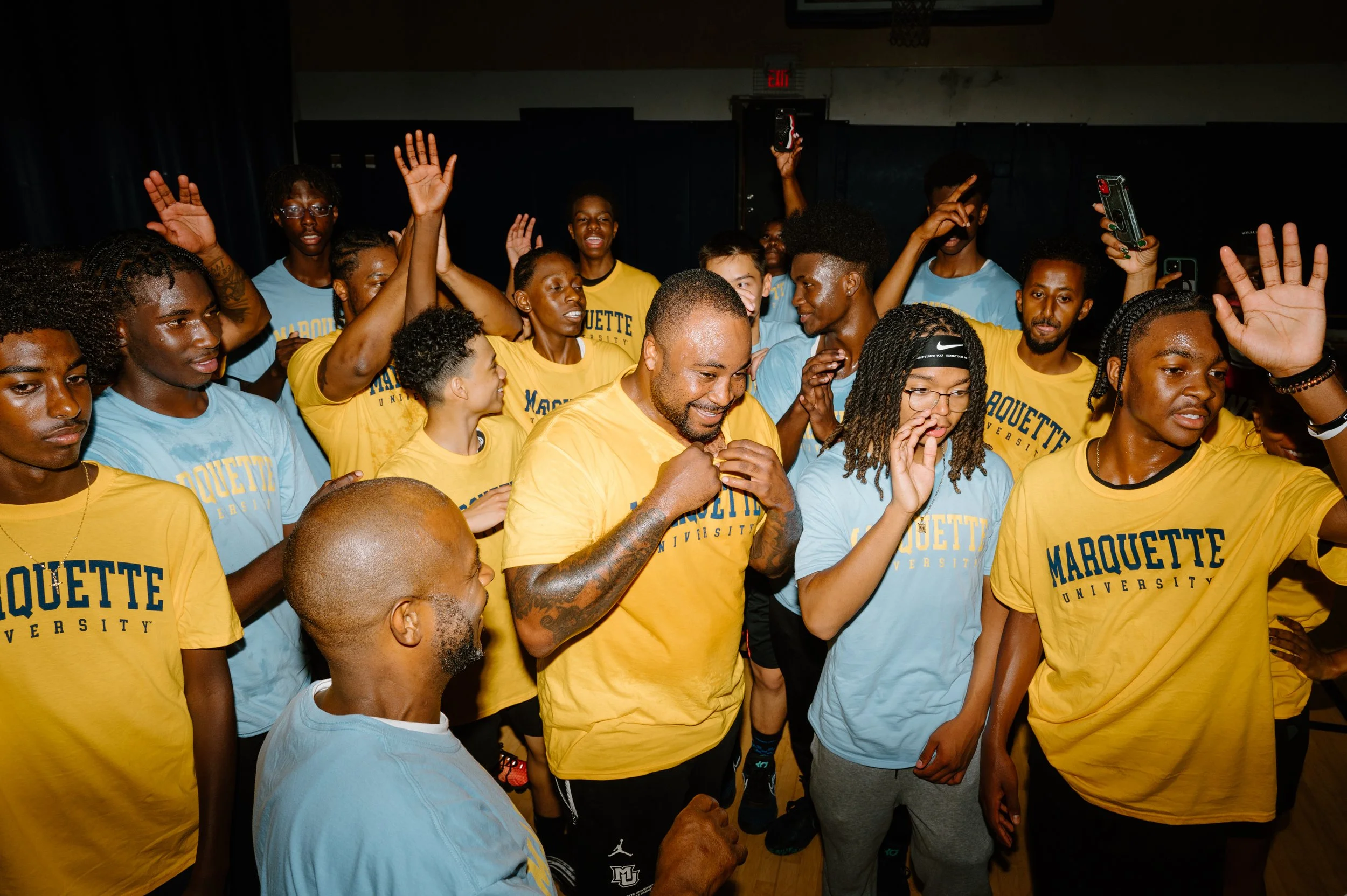 Candid editorial photo of the Marquette basketball team smiling and waving goodbye to the camera at the end of practice