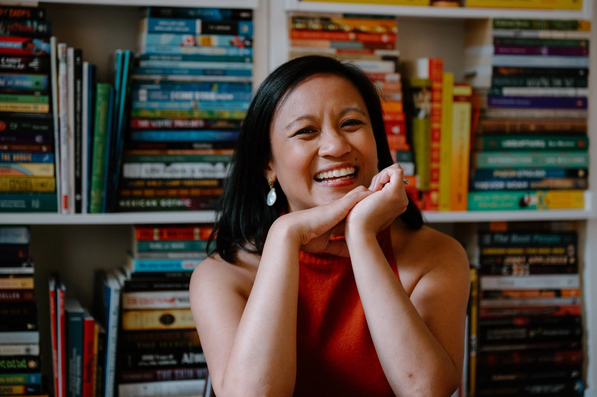 Close up editorial portrait of author Jennilee Austria-Bonifacio in front of her bookshelf at home in Toronto