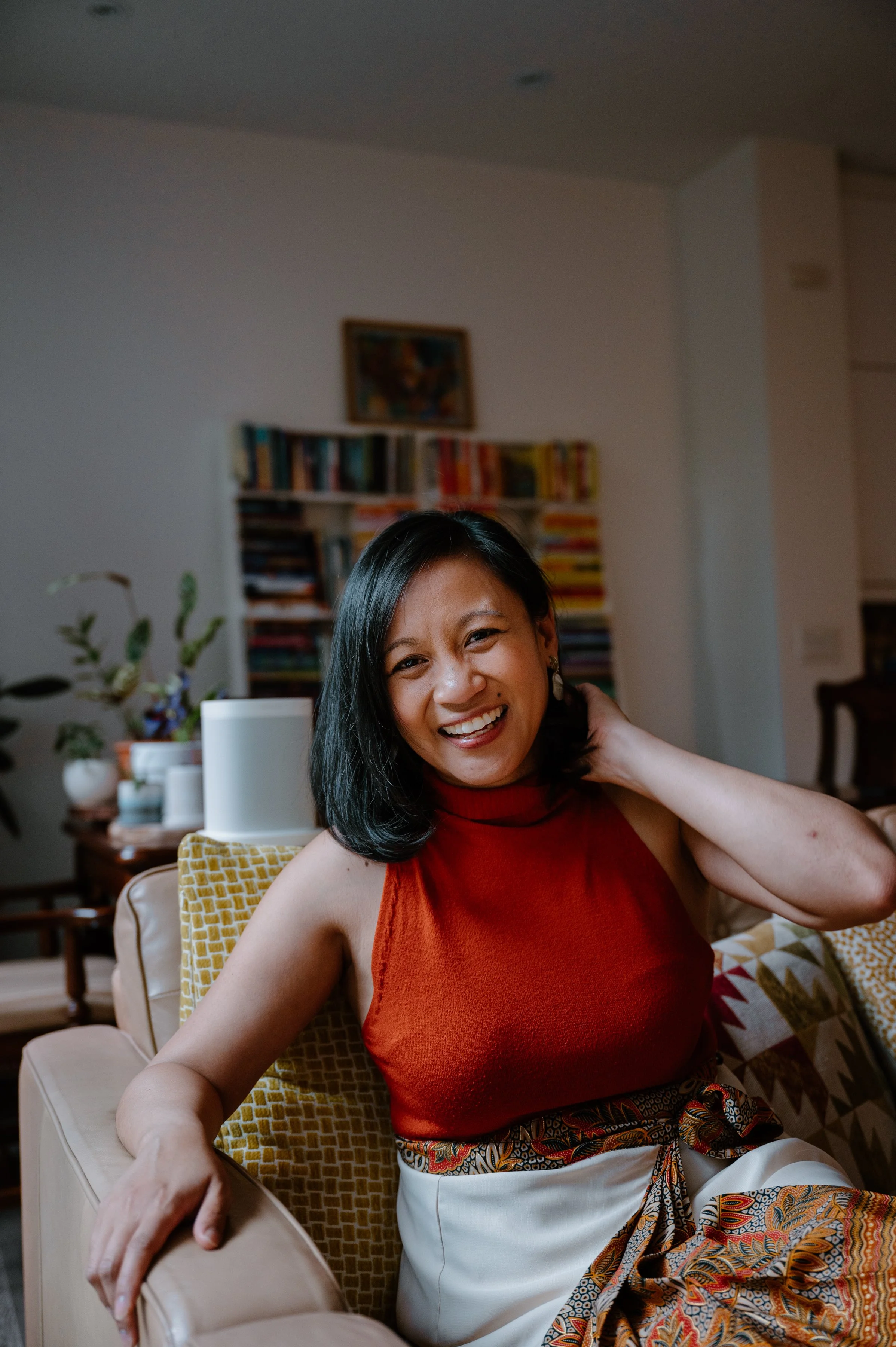 Authentic lifestyle portrait of Jennilee Austria-Bonifacio smiling on her couch wearing a traditional Filipino baro't saya at home in Toronto