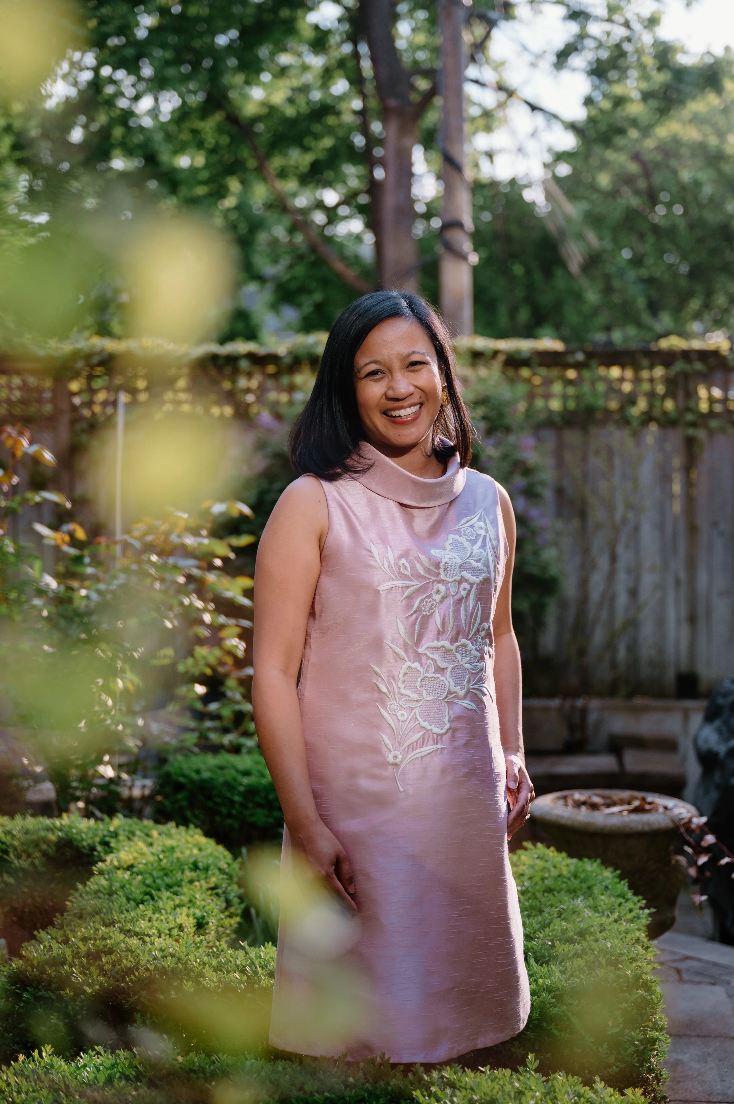 Editorial portrait of Filipino-Canadian author Jennilee Austria-Bonifacio standing in a garden in traditional dress with warm sunset light behind her