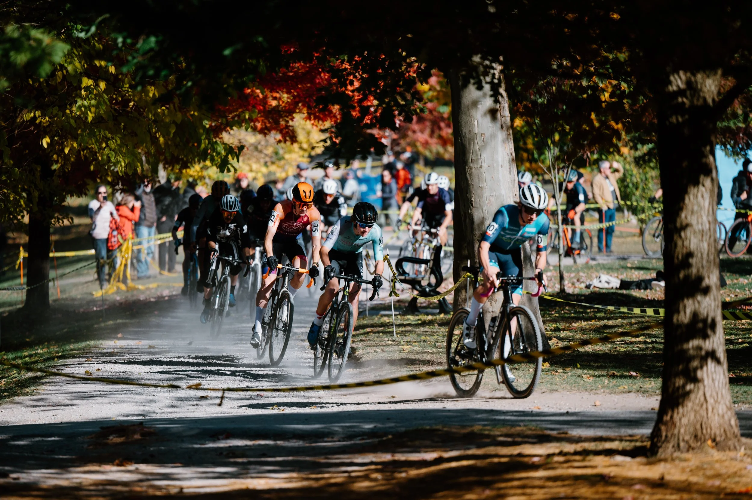 Editorial lifestyle photo of a large group of cyclocross riders racing through the open flat terrain at Christie Cross, Toronto
