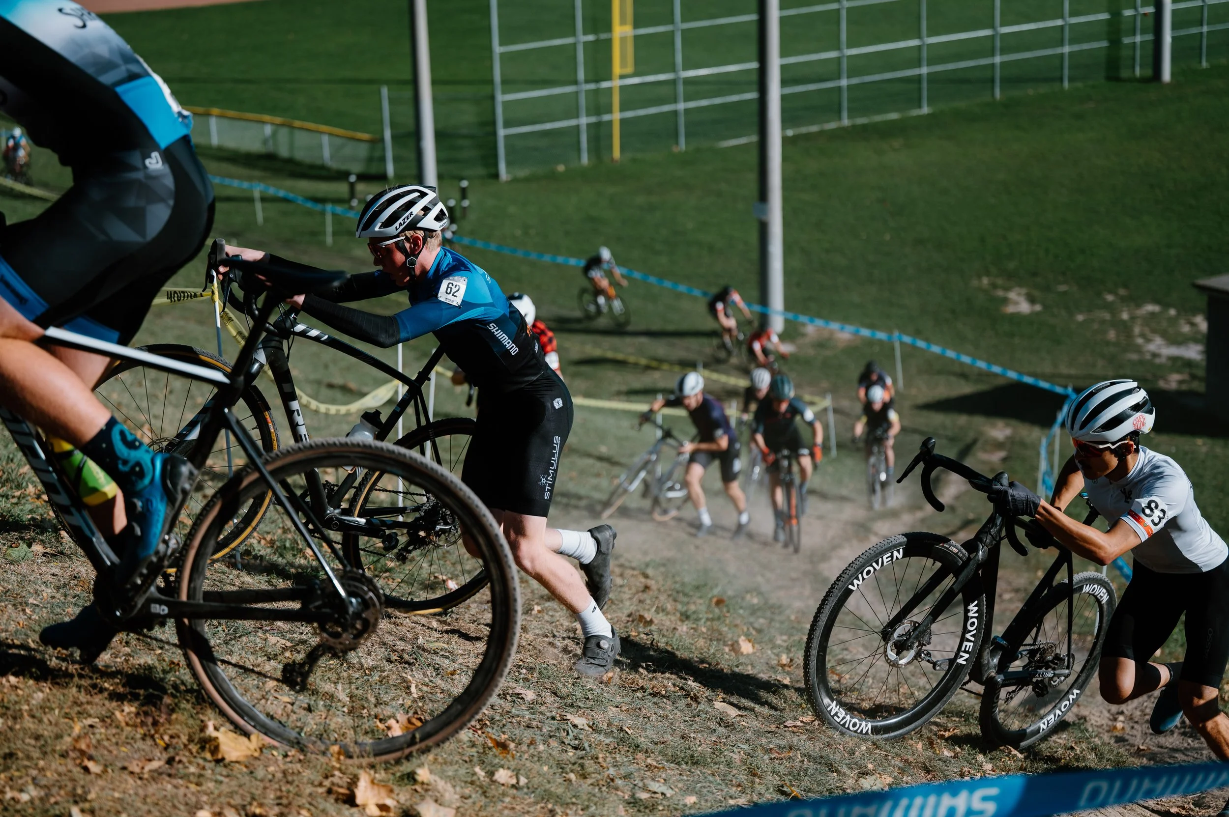 Cyclocross riders pushing uphill at Christie Pits Park in Toronto, suited for a Rapha cycling brand campaign