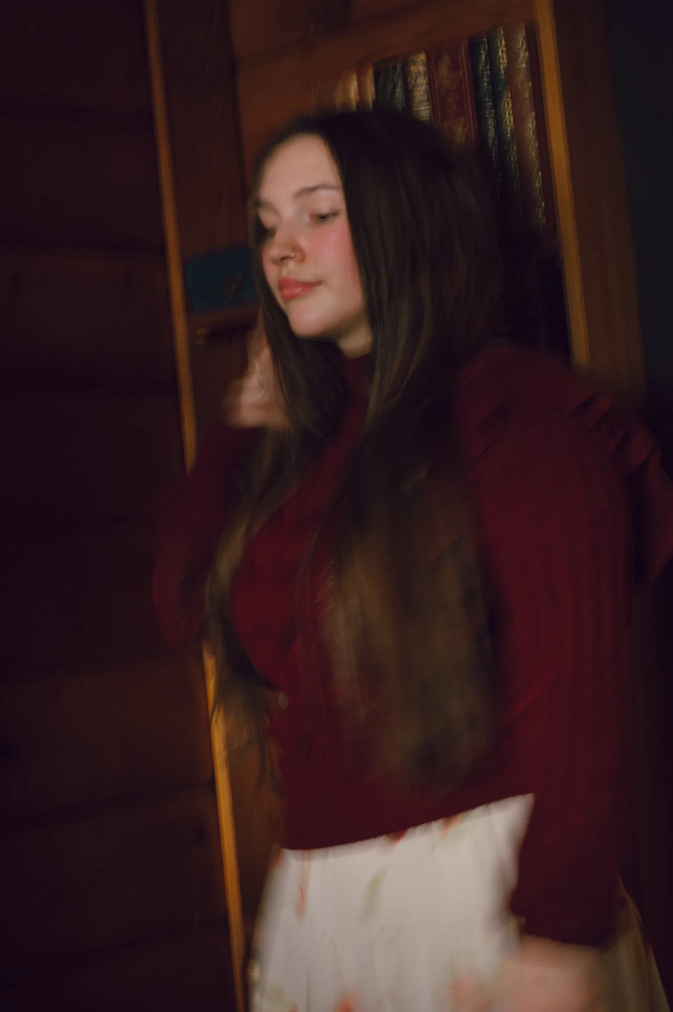 Editorial close portrait of a model near a bookshelf inside a pan abode cottage in Sooke BC, with soft motion blur adding movement
