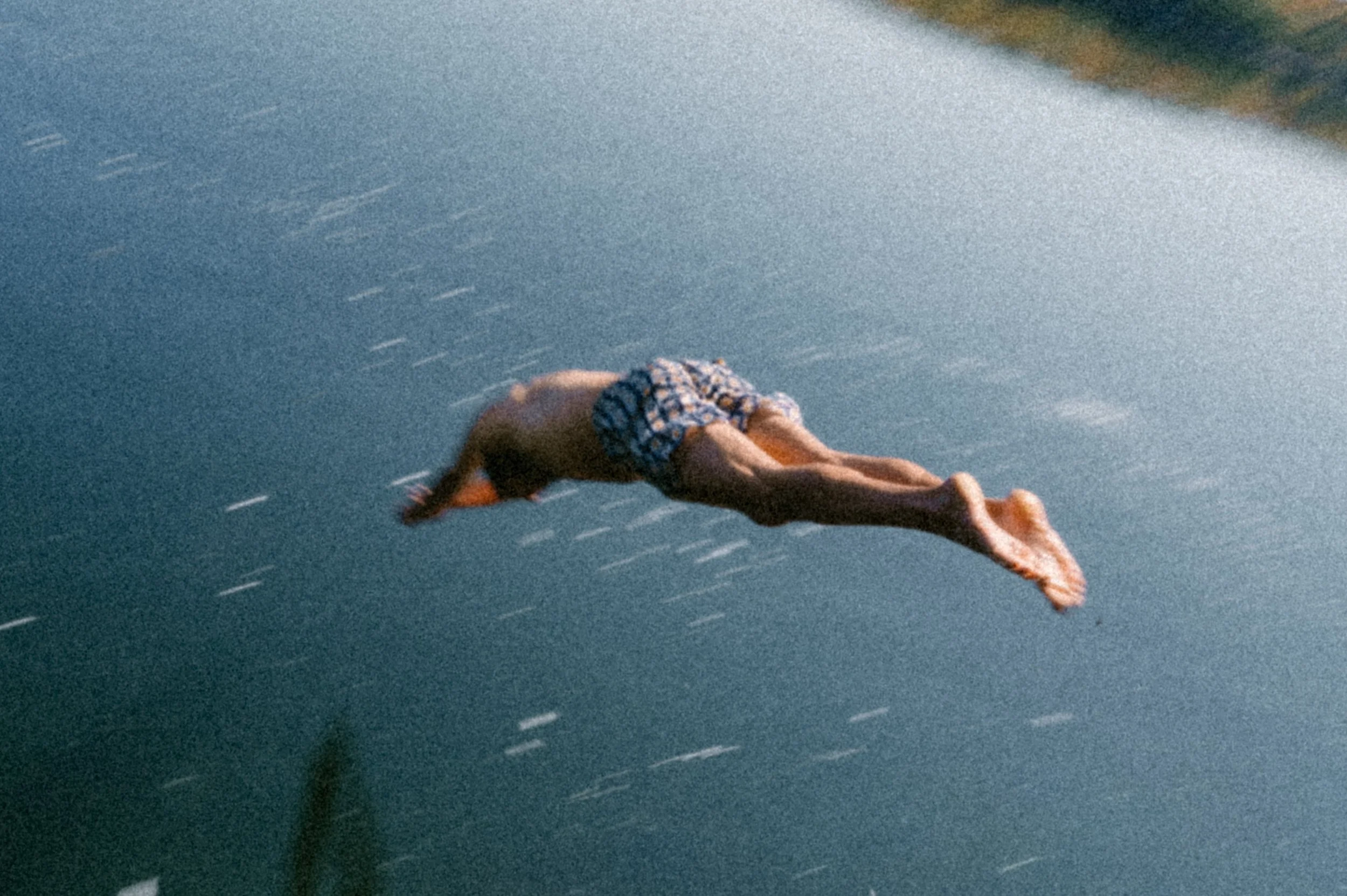 Lifestyle campaign photo of a person jumping into the water wearing Bather swim trunks, captured with natural motion blur
