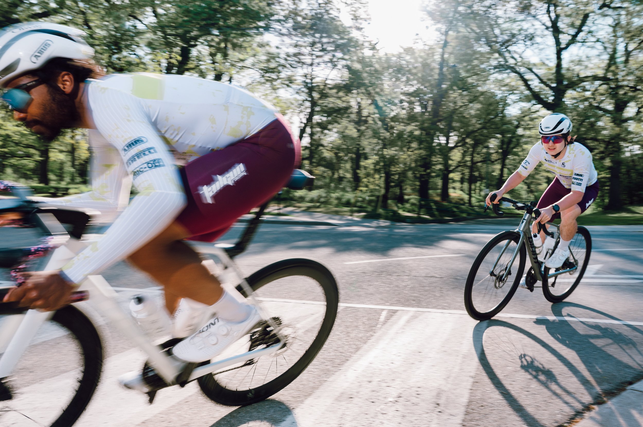 Two road cyclists taking a sharp corner low and in motion at High Park, suited for a cycling brand campaign