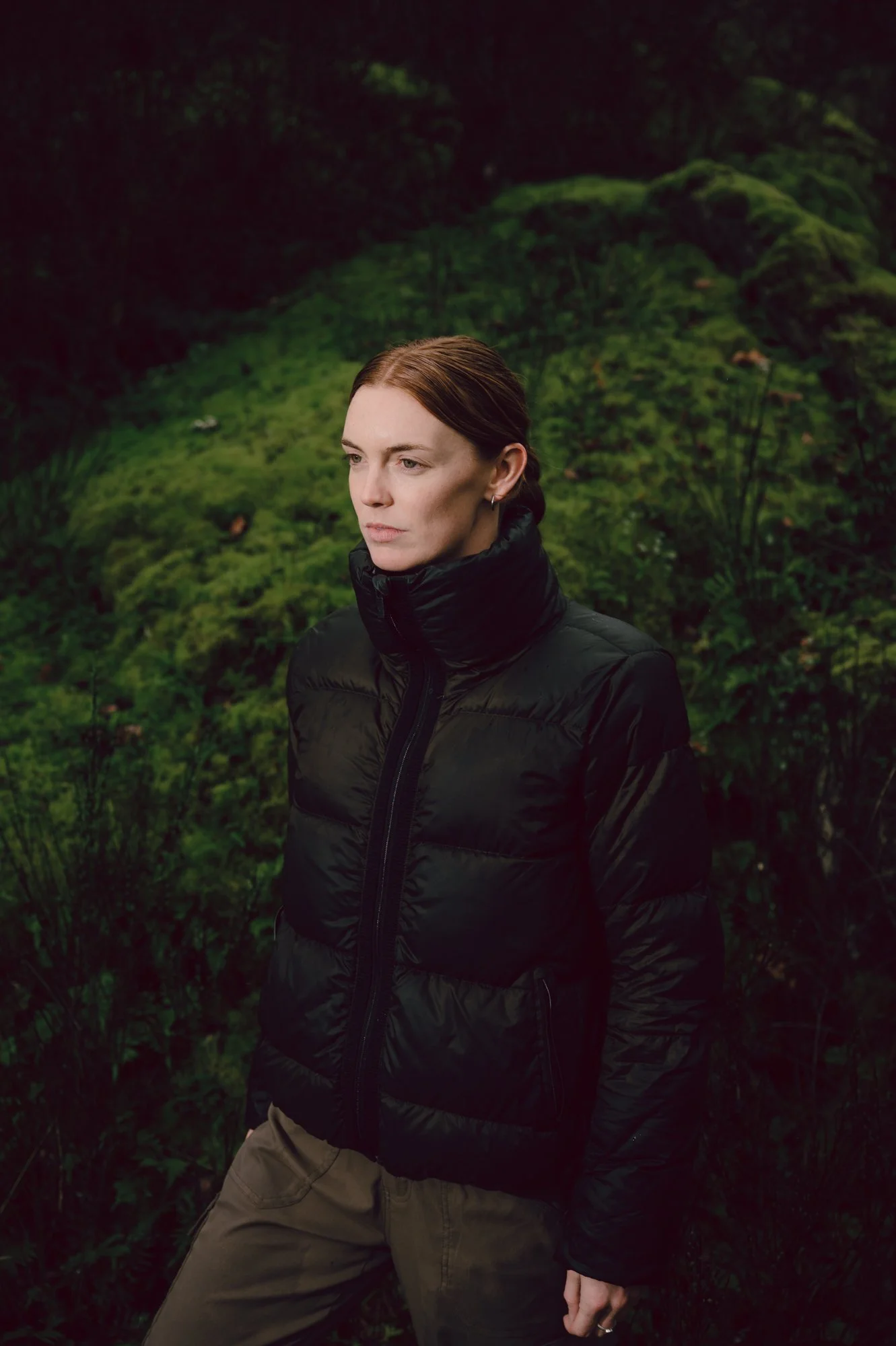 Authentic lifestyle portrait of a model gazing into the distance amid the lush greenery of Victoria BC, suited for an outdoor apparel brand