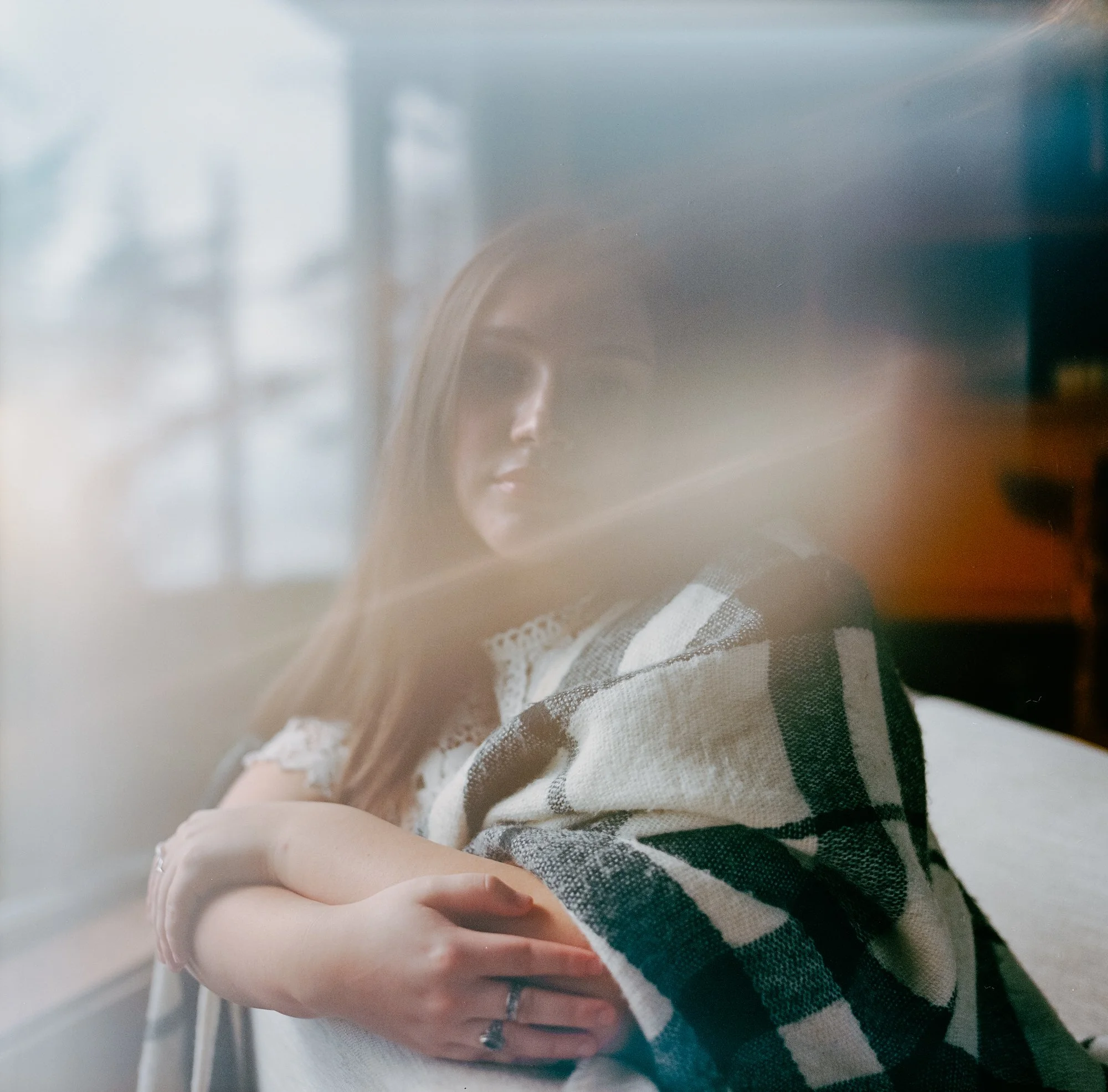 Experimental film photo of a model sitting by a cottage window in Victoria BC, with an organic processing glitch adding a creative and textured quality