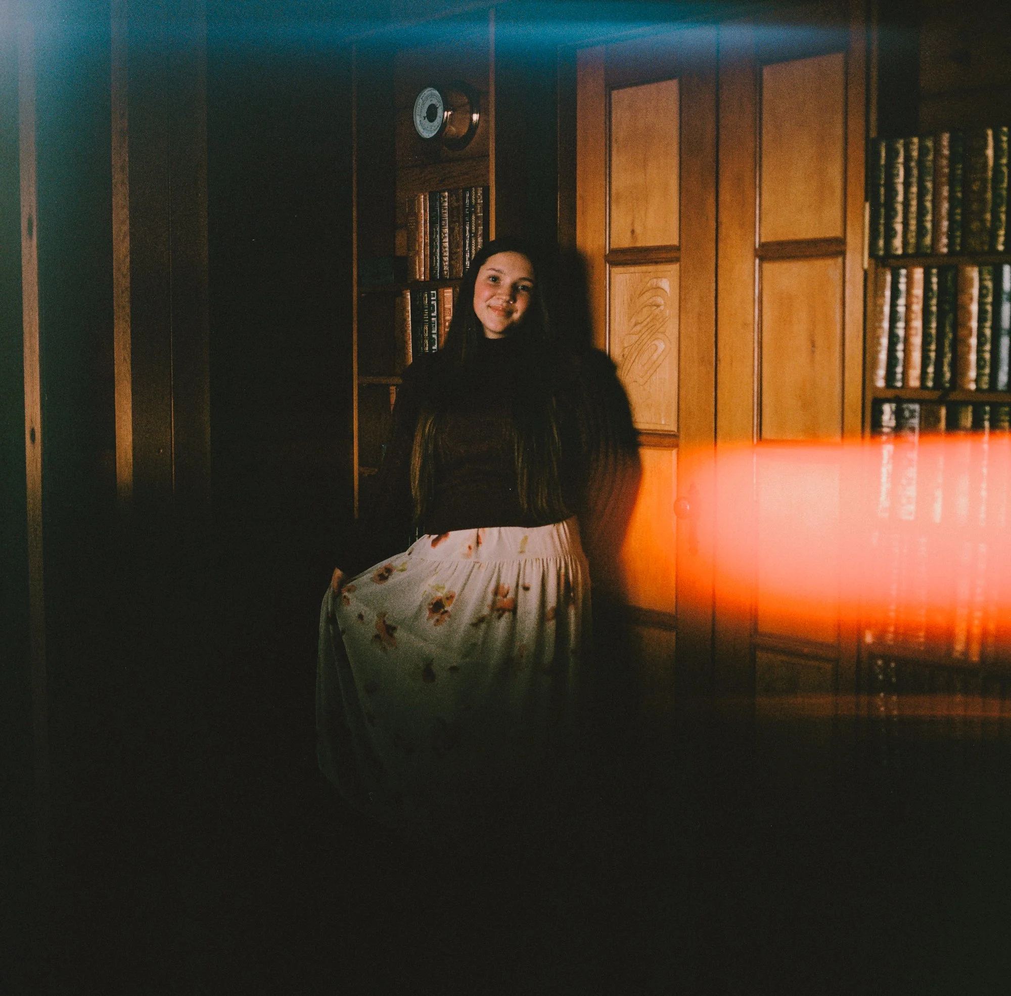 Film photo of a model inside a warm pan abode cottage in Sooke BC, with a natural light flare adding texture to the image