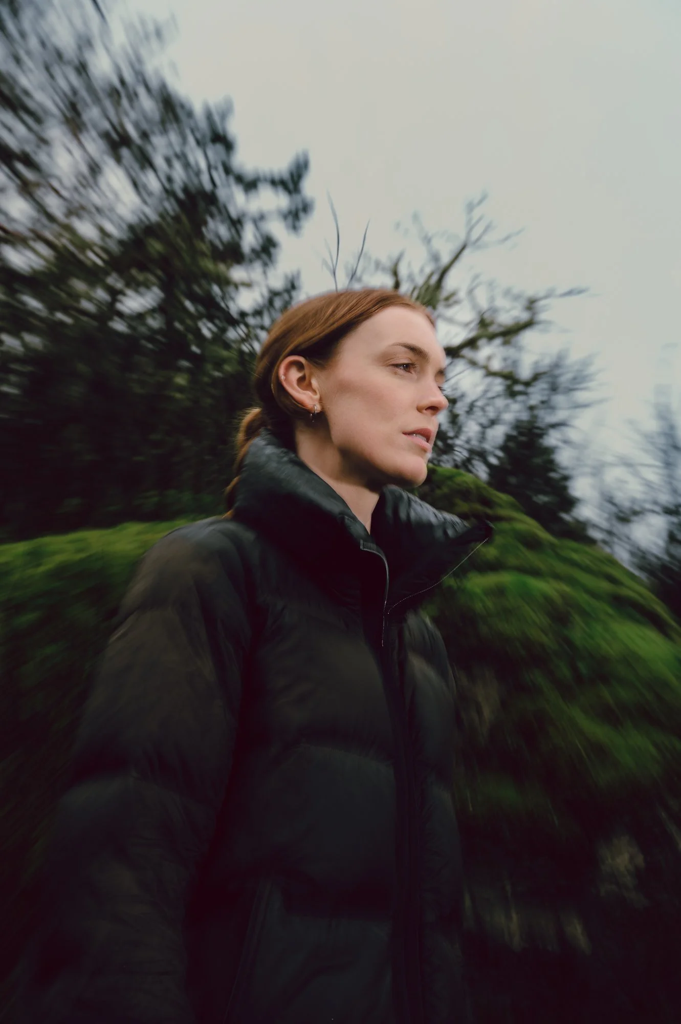 Editorial-inspired portrait of a model in motion with soft blur, wearing athleisure apparel among the mossy terrain of Thetis Lake BC