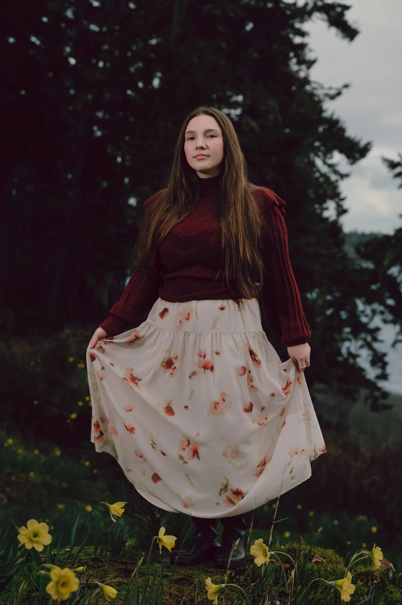 Dramatic editorial portrait of a model on a hillside in Sooke BC with wildflowers in the foreground and moody natural lighting