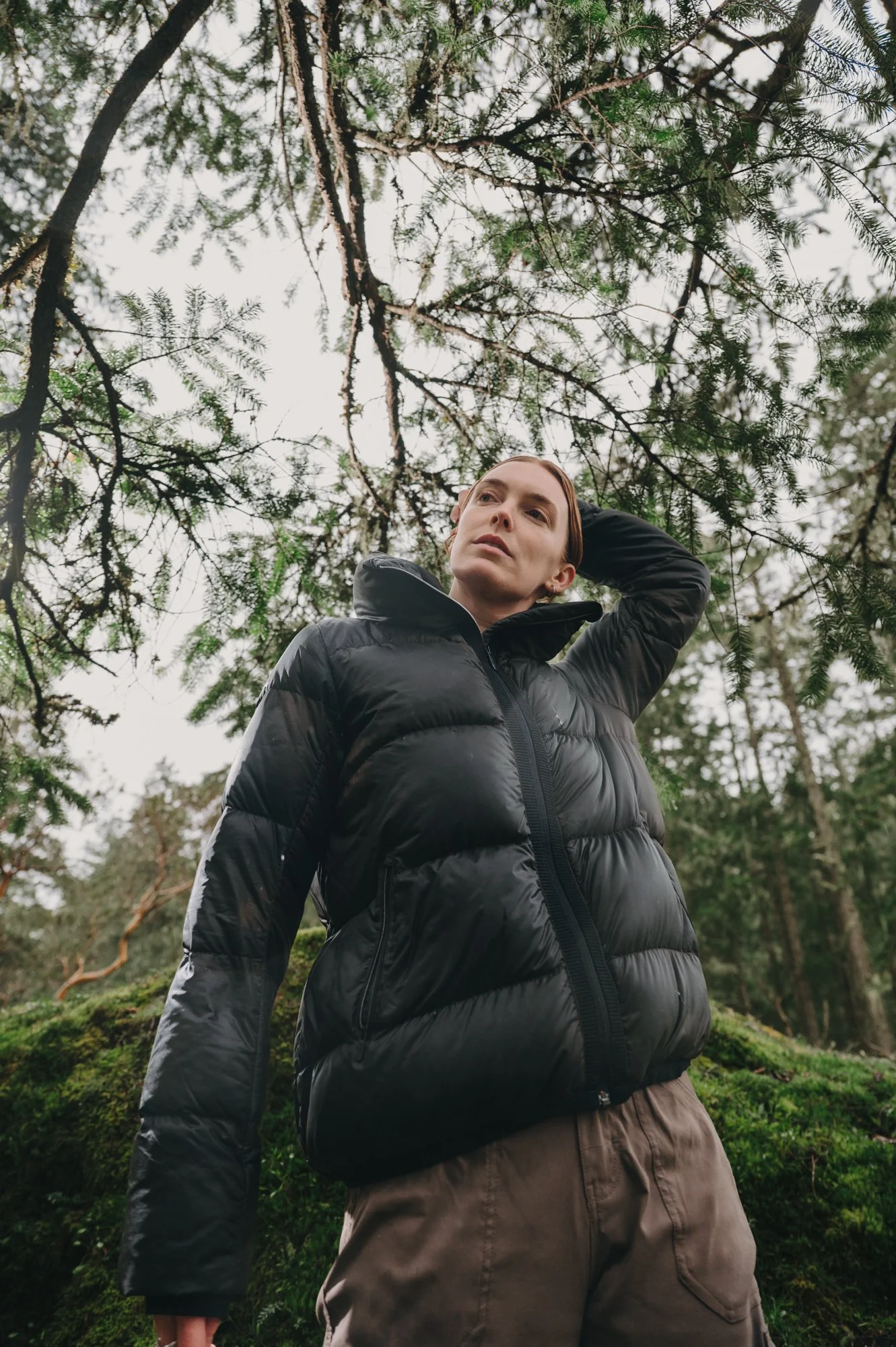 Wide commercial photography portrait of a model moving through a mossy forest landscape on Vancouver Island, natural and authentic