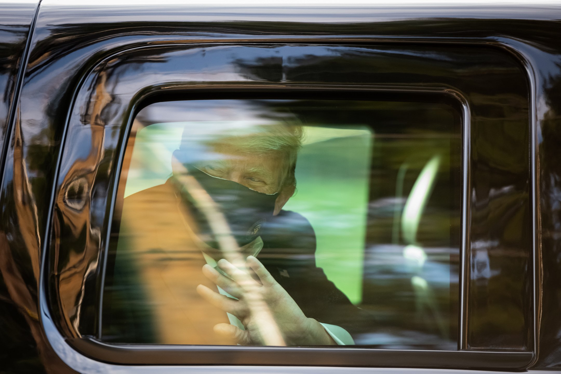  President Donald Trump wears a protective mask while waving as he is driven in a motorcade past supporters outside of Walter Reed National Military Medical Center, during his stay there after being diagnosed with COVID-19, in Bethesda, MD, on Octobe