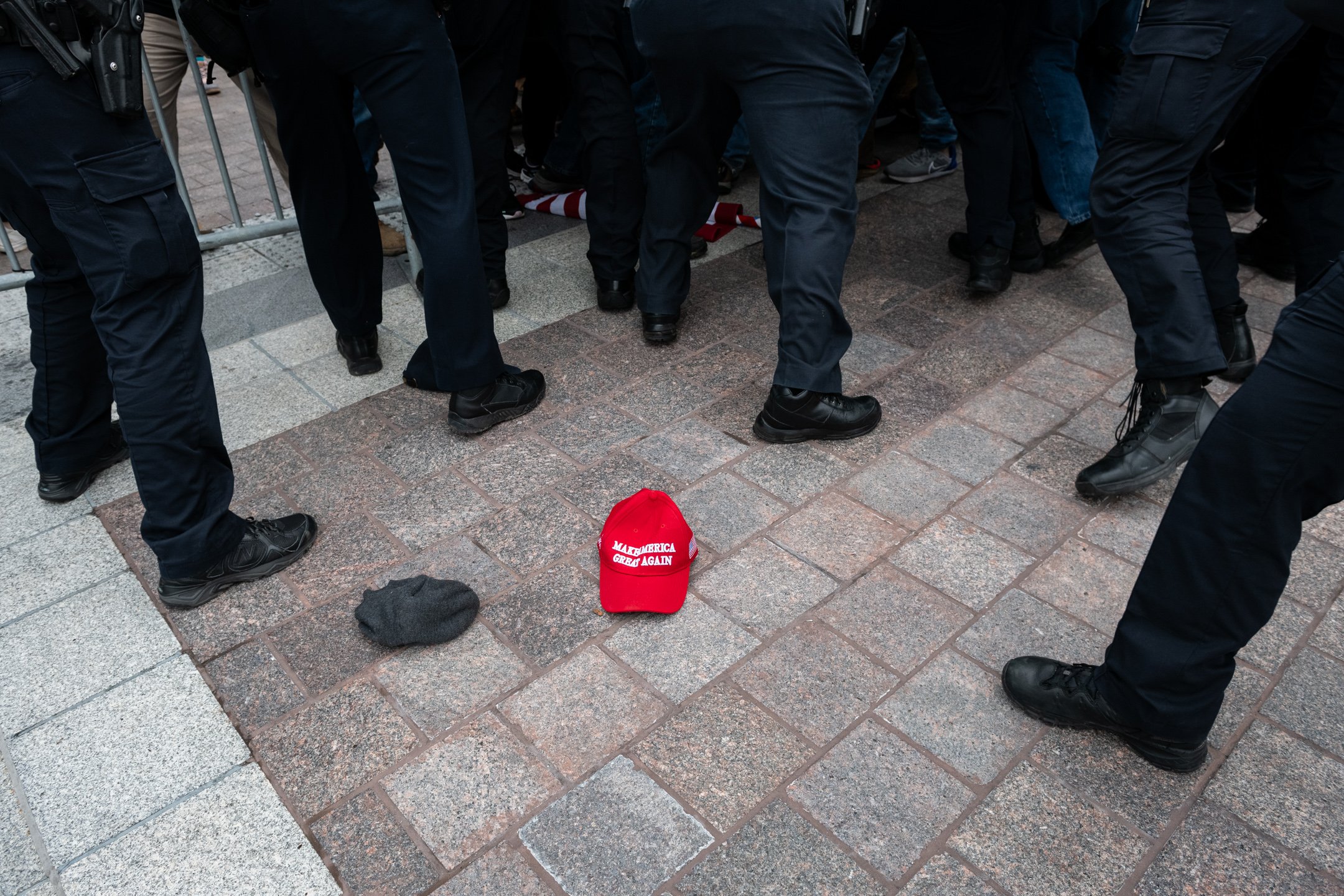  A “Make America Great Again” hat rests on the ground as Capitol Police officers struggle to hold back pro-Trump rioters during the January 6 insurrection, outside the U.S. Capitol, in Washington, D.C., on January 6, 2021. (Graeme Sloan for Bloomberg