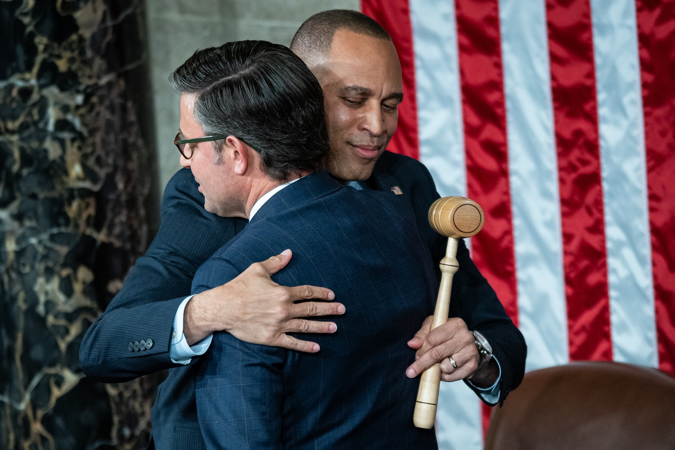  Representative Hakeem Jeffries (D-N.Y.), the House Minority Leader, embraces Representative Mike Johnson (R-LA) after Johnson’s election to be Speaker of the House, while directing an apparent hand gesture toward the Republican side of the aisle, in