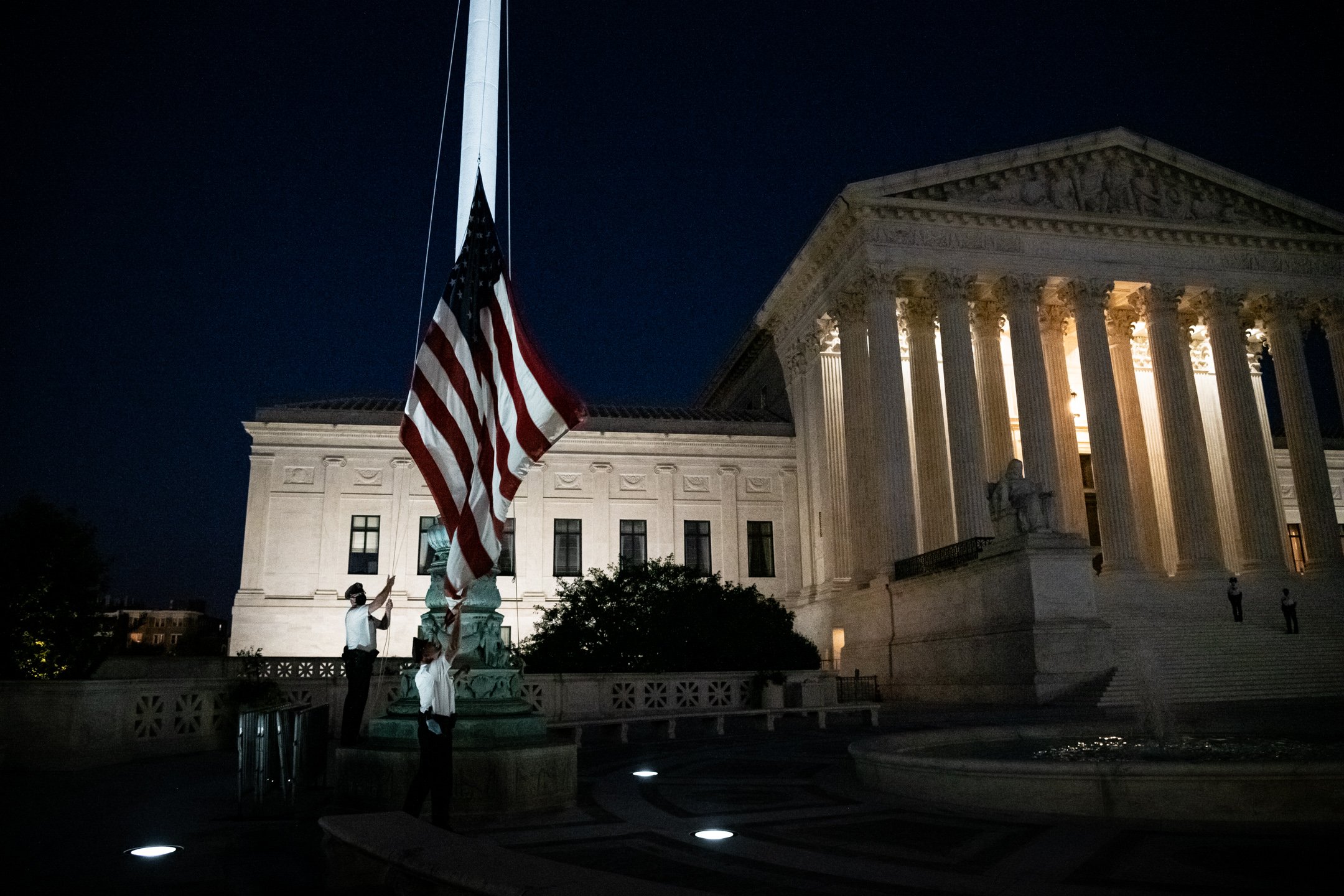  Police officers lower the American flag to half staff outside the U.S. Supreme Court, moments after the passing of Justice Ruth Bader Ginsburg at the age of 87, in Washington, D.C., on September 18, 2020. (Graeme Sloan/Sipa USA) 