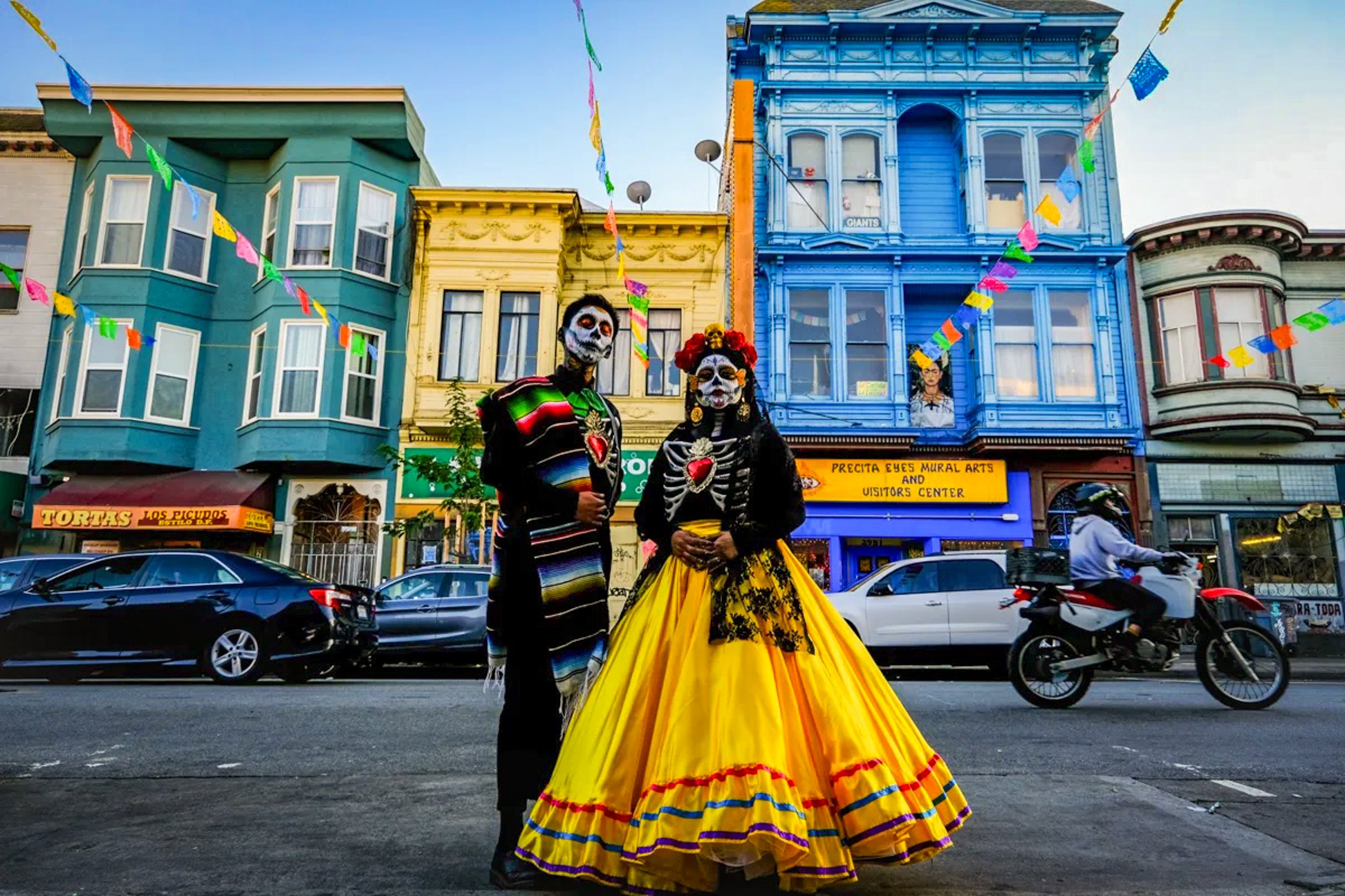  Alan and Montse of  Las Tres Brujas , who create and customize artesaías and flower crowns, pose on 24th Street in the Mission District of San Francisco, Calif. during the 2021 Die De Los Muertos celebrations. 