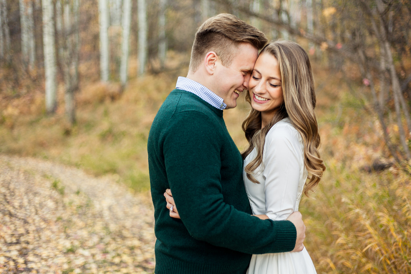 Eliza and Josh chose to have their engagement pictures done in the beautiful fall leaves! Josh chose a dark green sweater that perfectly contrasted the foliage, and Eliza wore an off-white dress that contrasted Josh. Notice Josh’s subtle pattern with his button-up shirt underneath his sweater!