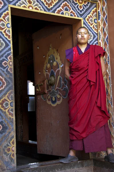 A Buddhist monk stands alongside the doorway of a temple as if to say, “Welcome to the Kingdom of Bhutan also known as the ‘Kingdom of Happiness’”. Enjoy your visit.