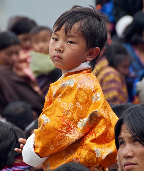 A young boy dressed in his finest brocade is transfixed with the dance dramas taking place.