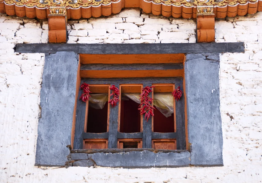 Red chillies hang from a window to dry. Bhutan’s national dish is very hot chillies (either green or red) in a cheese sauce served as a vegetable dish, not as a seasoning. It is absolutely mouth-scorching.