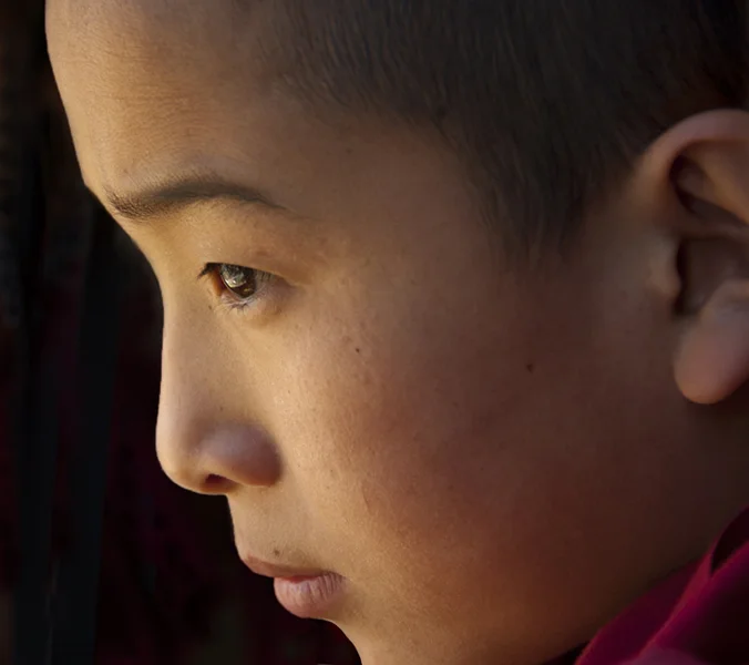 A monk intently watches the religious ceremony going on outside the Paro Dzong. That ceremony observed in the reflection in his eye.