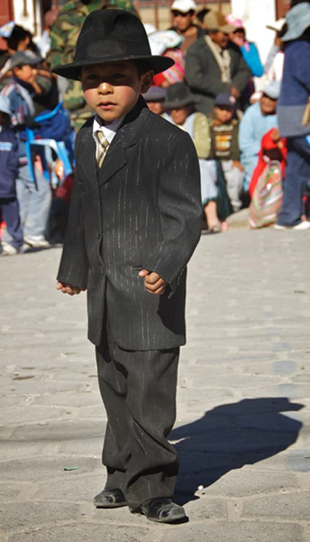 A young Bolivian boy, in formal dress, takes part in a religious celebration in Uyuni.