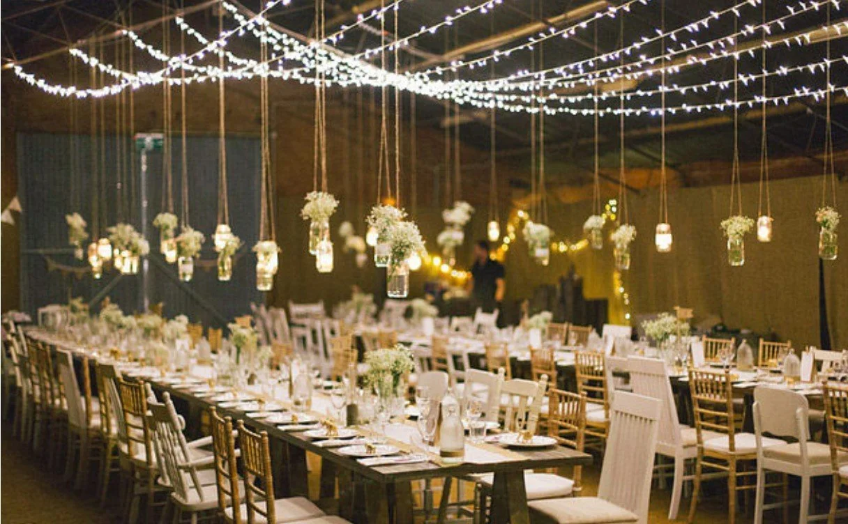 Inside barn wedding reception with pretty fairy lights and glass vases hanging from the ceiling_Brisbane Barn Weddings_Brisbane North Wedding Venue