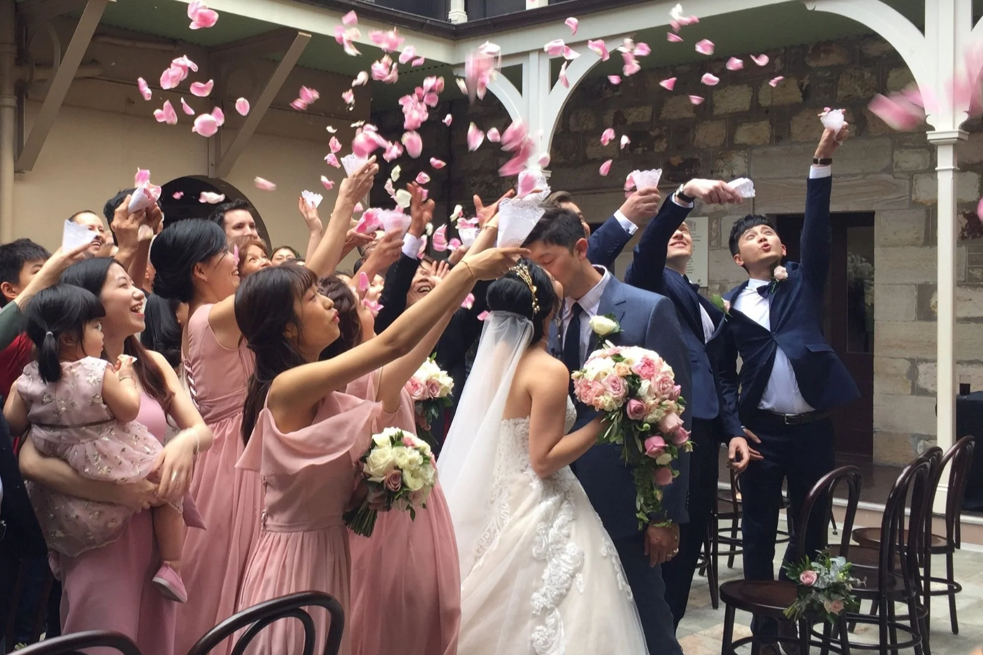 Wedding guests throw petals over wedding couple after their wedding at Old Government House Courtyard, Brisbane with Trudy the Brisbane Marriage Celebrant