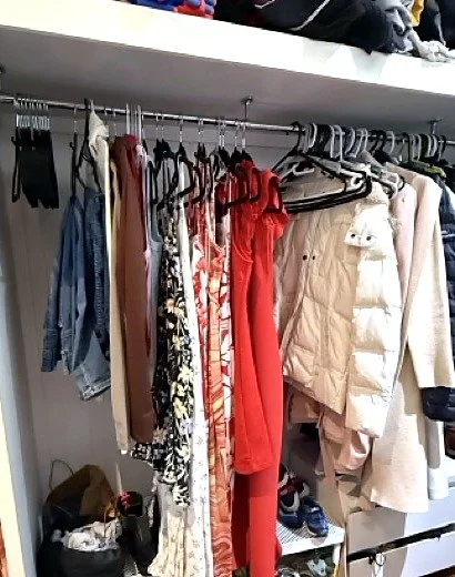 Crowded hanging rail of dresses, denim and jackets before a wardrobe audit