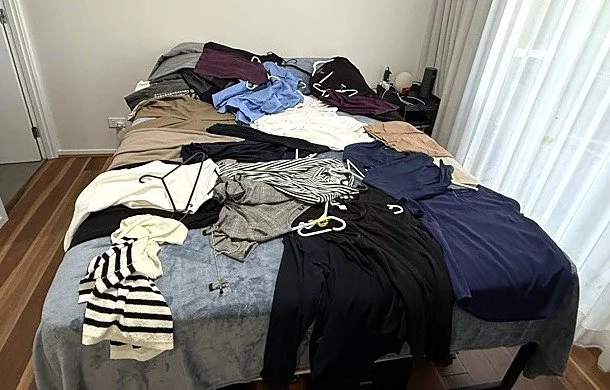 Clothes laid out on a bed to try on and sort during a wardrobe audit