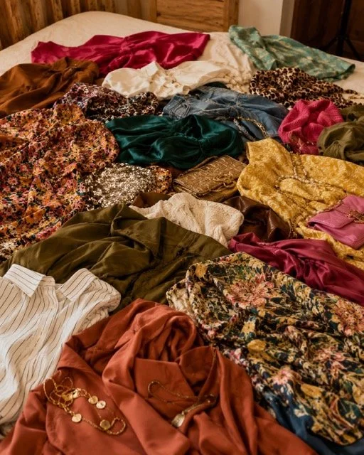 Colourful silk and printed clothes piled on a bed, a sign you may need a wardrobe audit