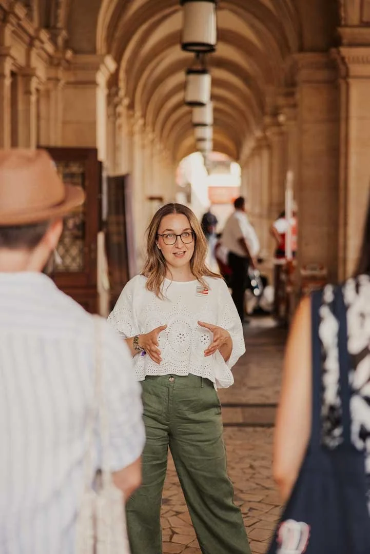 Tour guide on a private tour telling stories of the vampire hunter of Hietzing, standing in historic arcades with candles hanging from the ceiling, Vienna