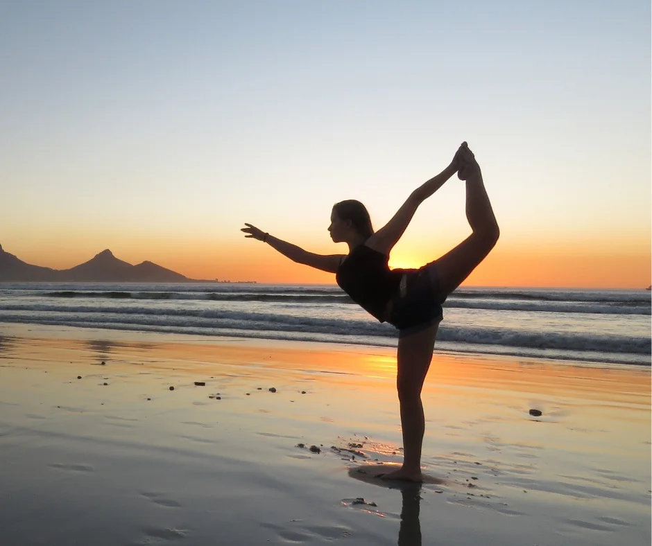 Woman doing a balance move on the beach.