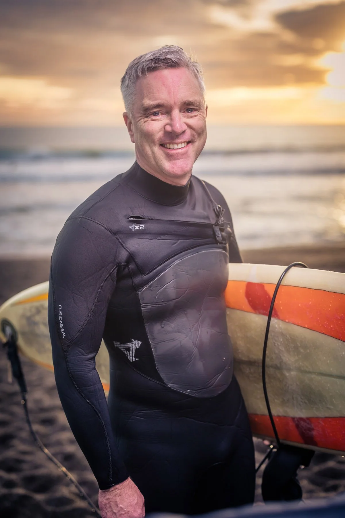 older man in wetsuit with surfboard