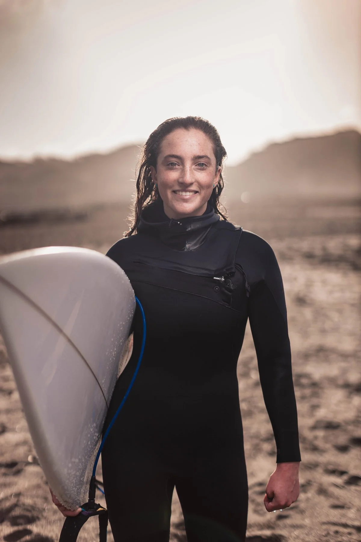 young woman in wetsuit with surfboard