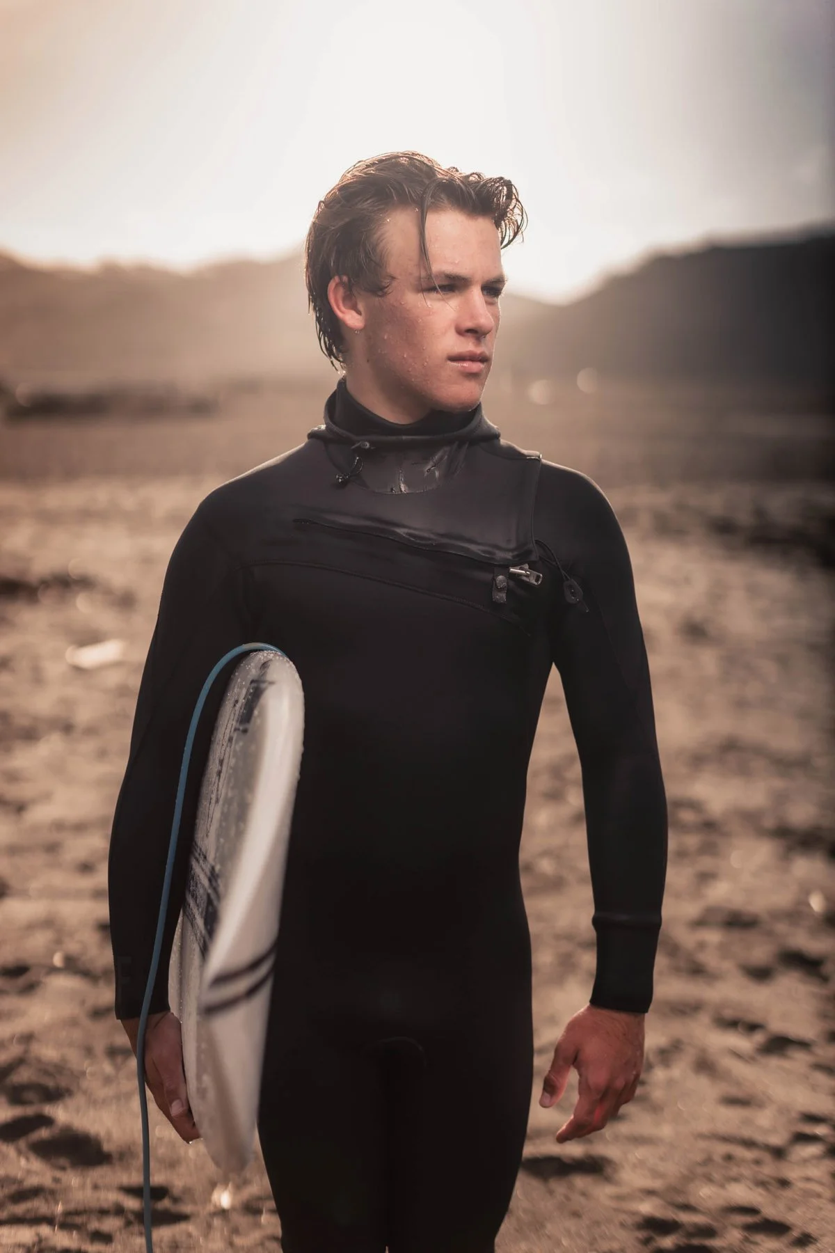 Man in wetsuit with surfboard on beach
