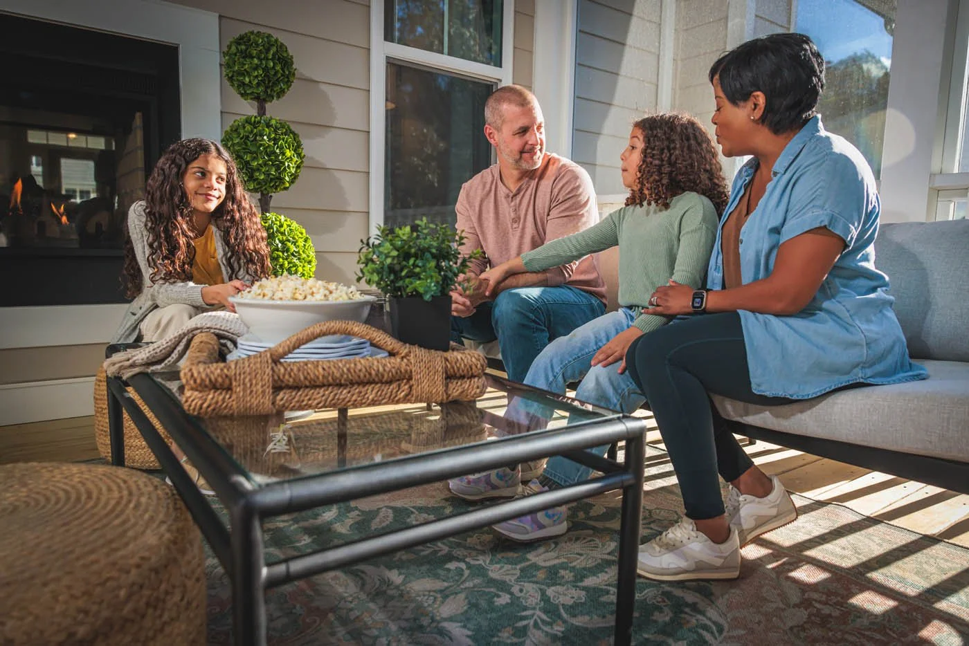 Lifestyle portrait of happy family of four on screened porch