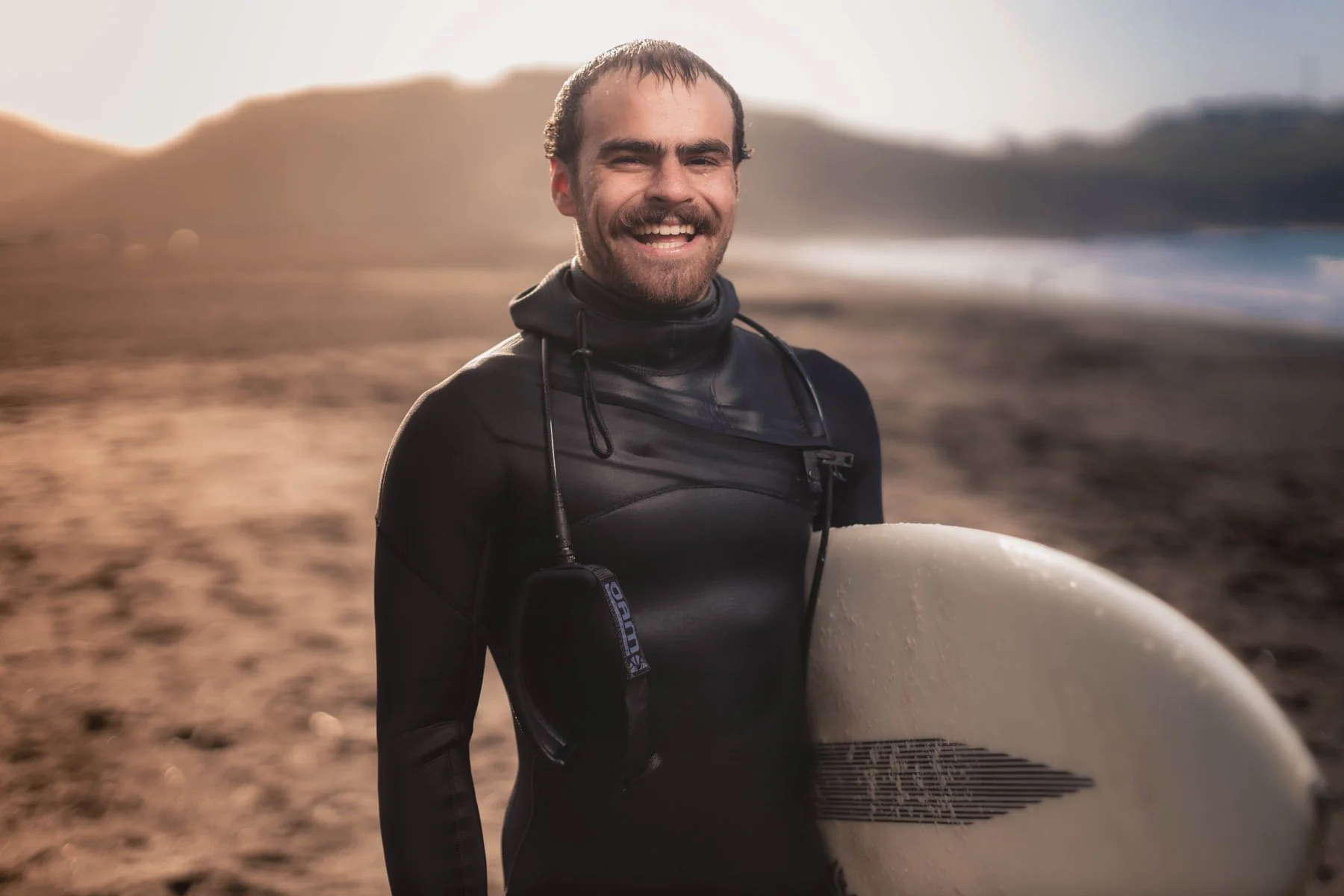 Smiling man with surfboard in California