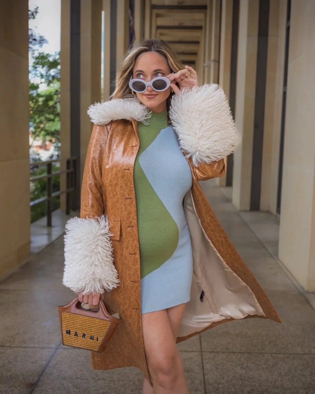 Woman in a retro coat and Marni bag stands in a corridor, perfect for a Branding photoshoot with vintage flair.