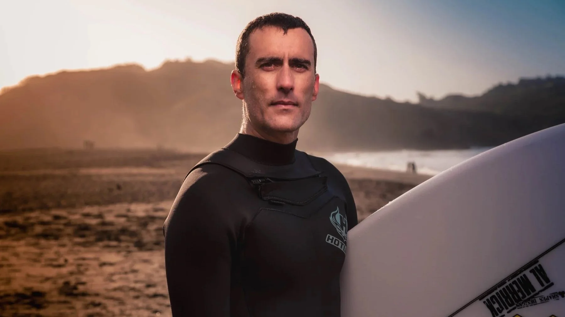 Serious looking man with surfboard on a beach