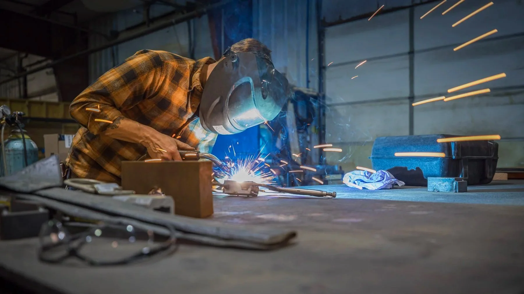 An Industrial Photographer Richmond captures a welder in action, sparks flying, and tools scattered across the bustling workshop.