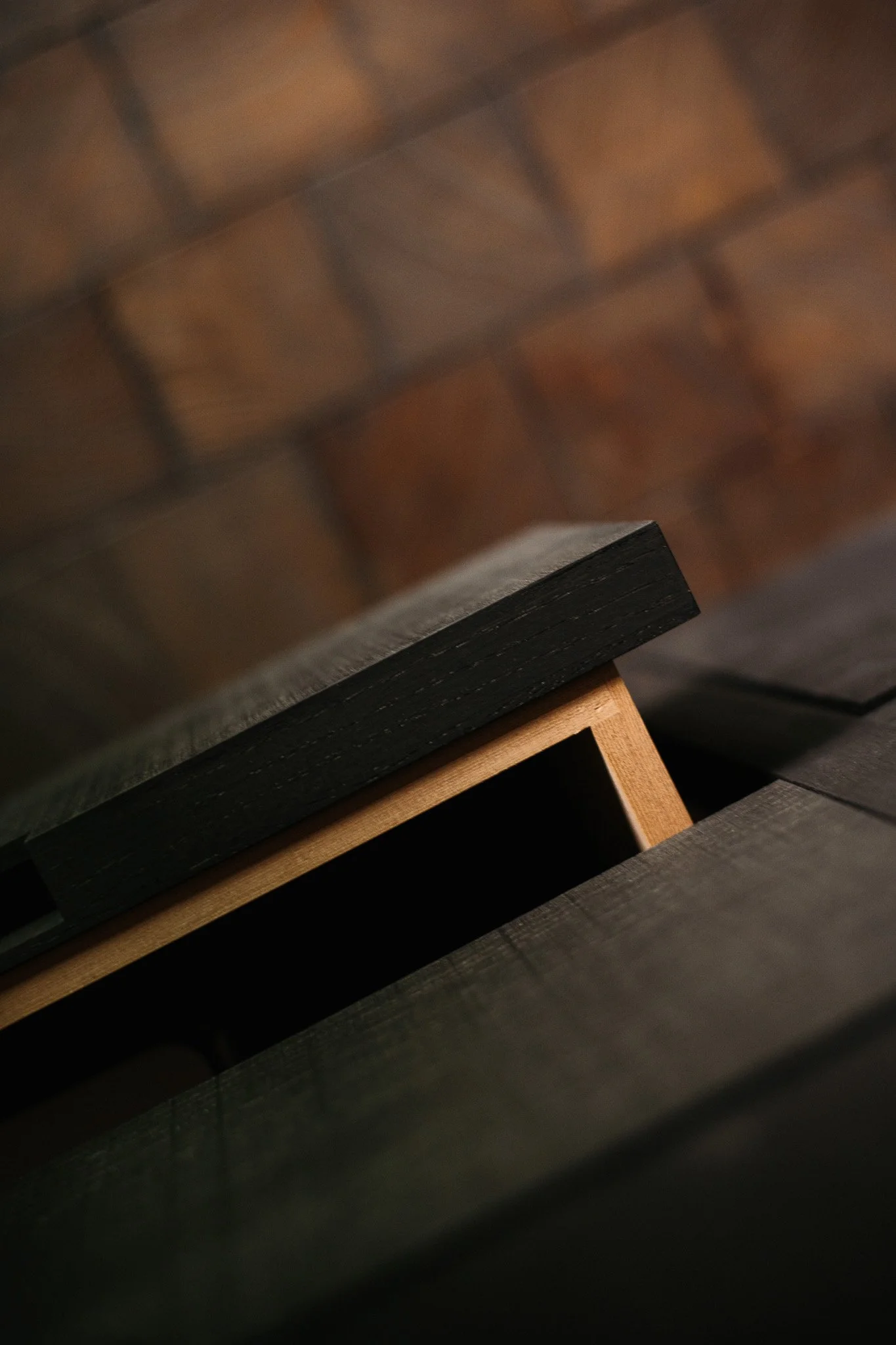 Close-up photo of a wooden bench with a brick wall in the background