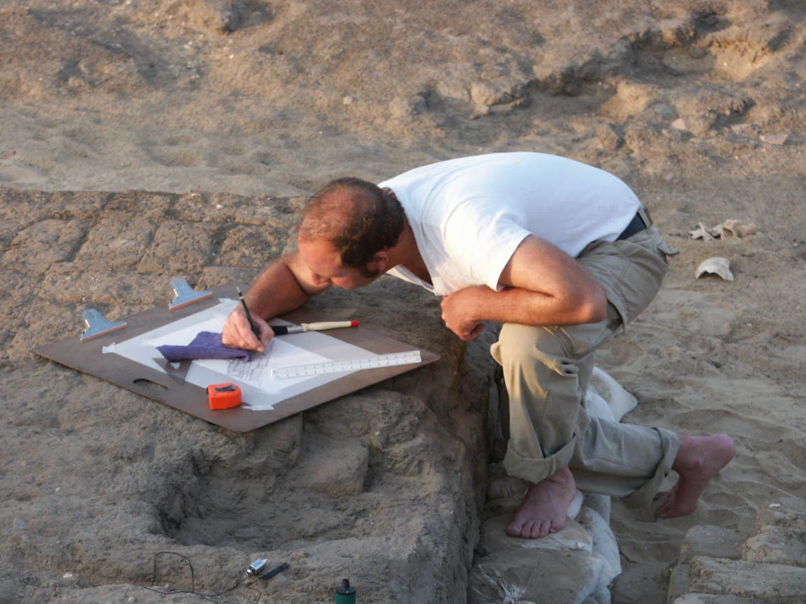 Fig. 1. Architectural illustrator Damon Cassiano planning a Middle Kingdom chapel in the Abydos North Cemetery. Photo: Robert Fletcher / North Abydos Expedition © 2003