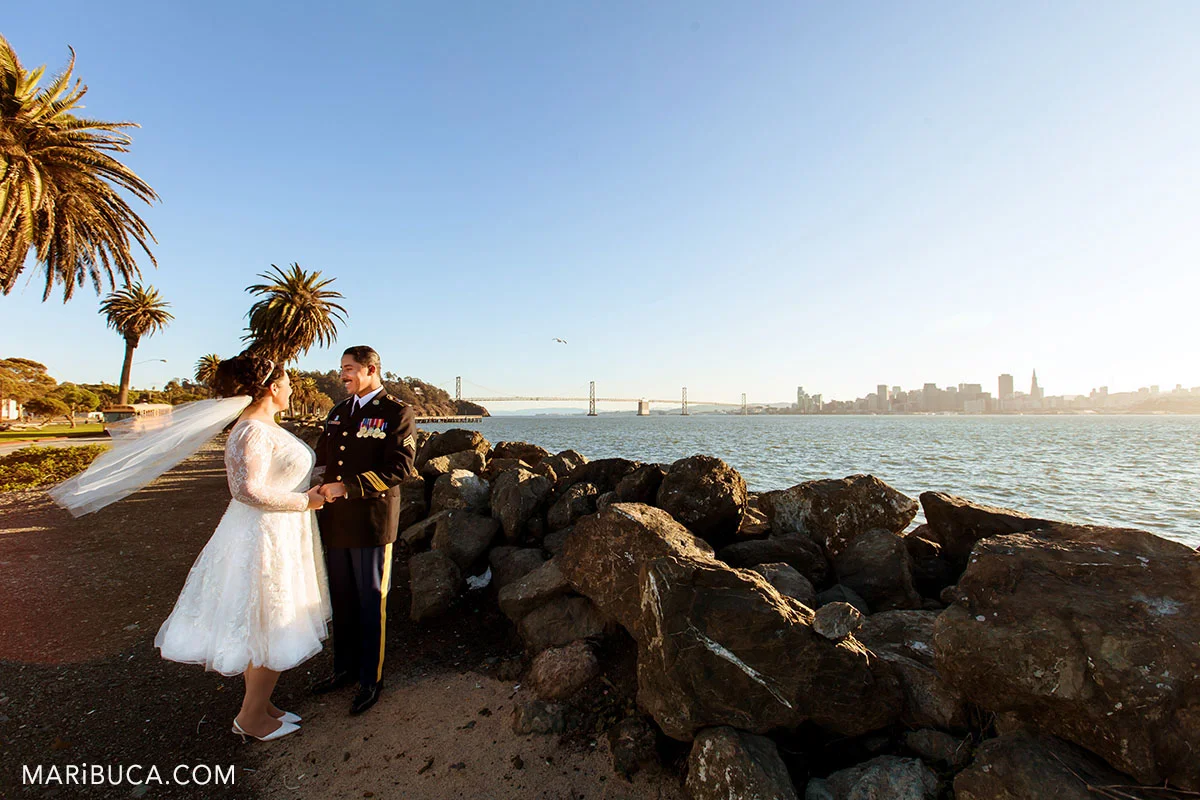 Newlyweds hubby and wifey look each other during the orange sunset in the treasure island, san francisco wedding