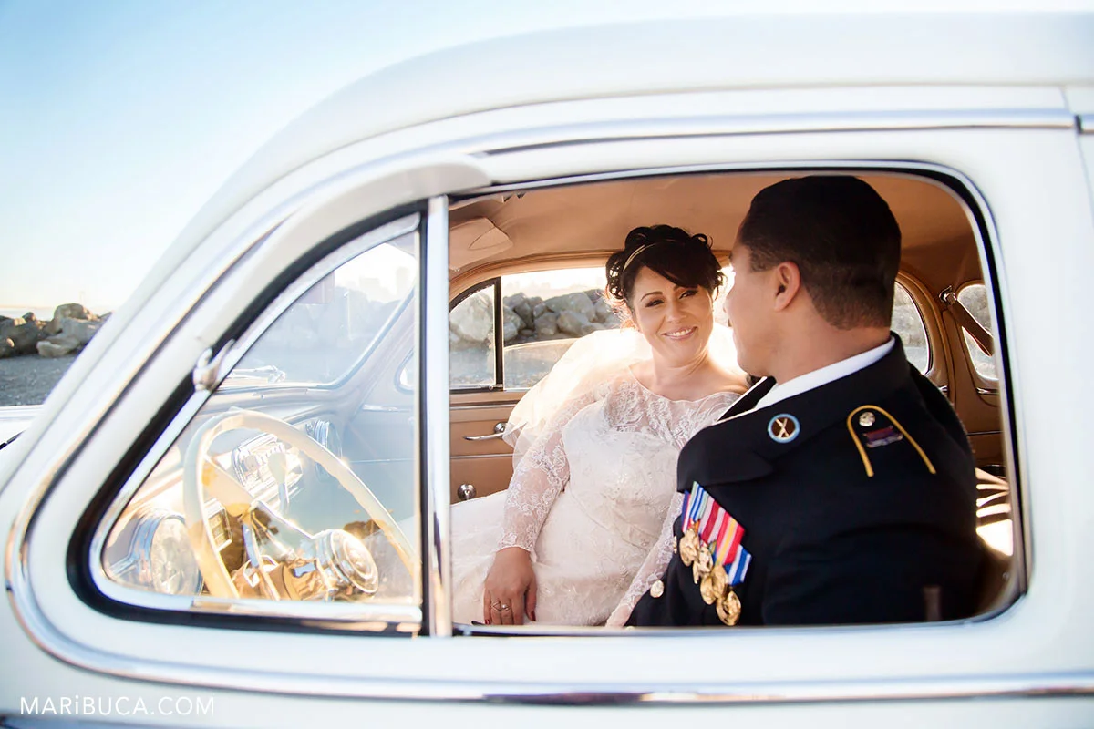 bride looking at the groom and they both are sitting in the pontiac in the Treasure Island, California