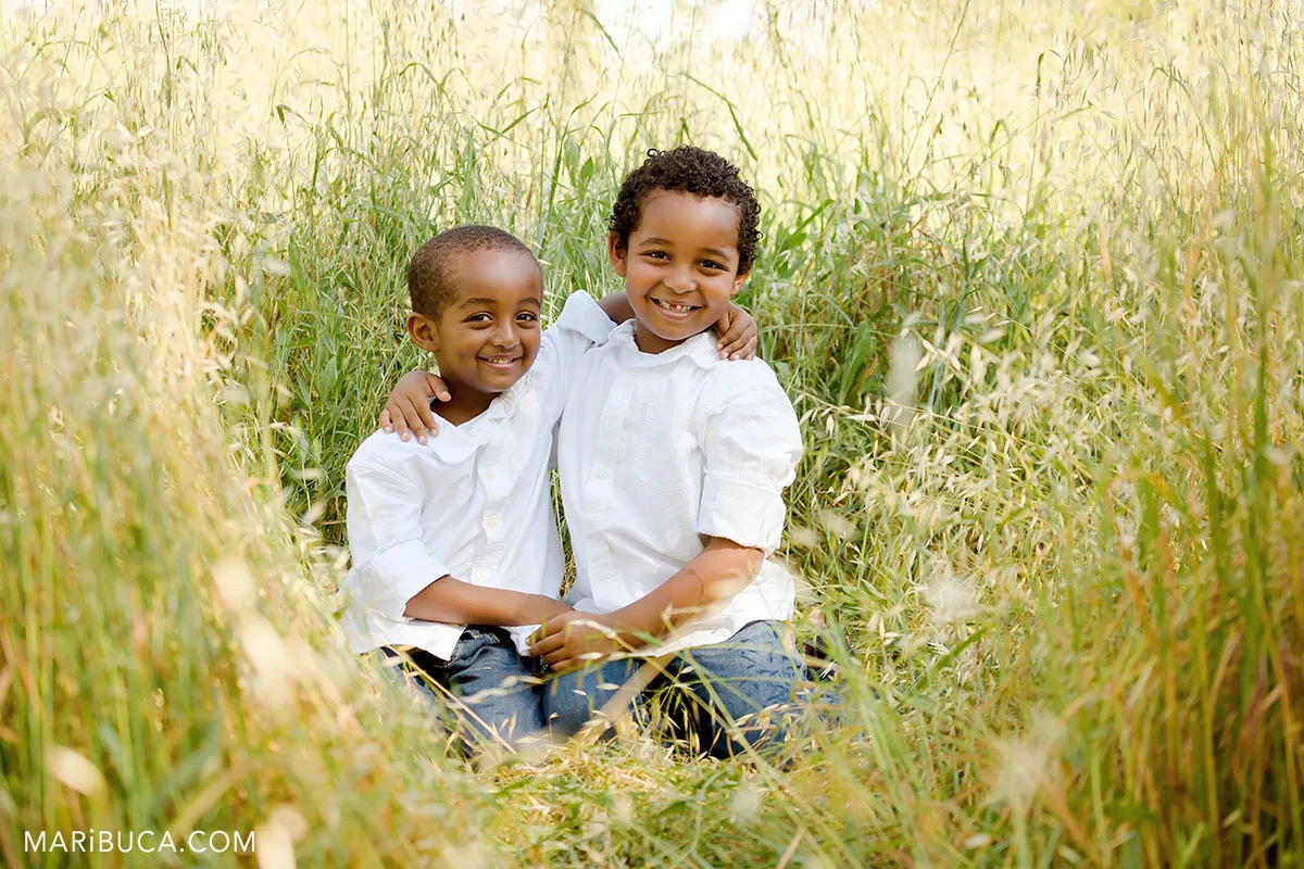 two brothers in the high grass sitting and smiling